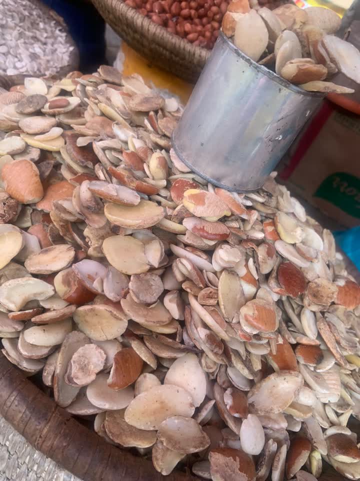 Flat tan ogbono wild mango seeds piled in a woven market basket