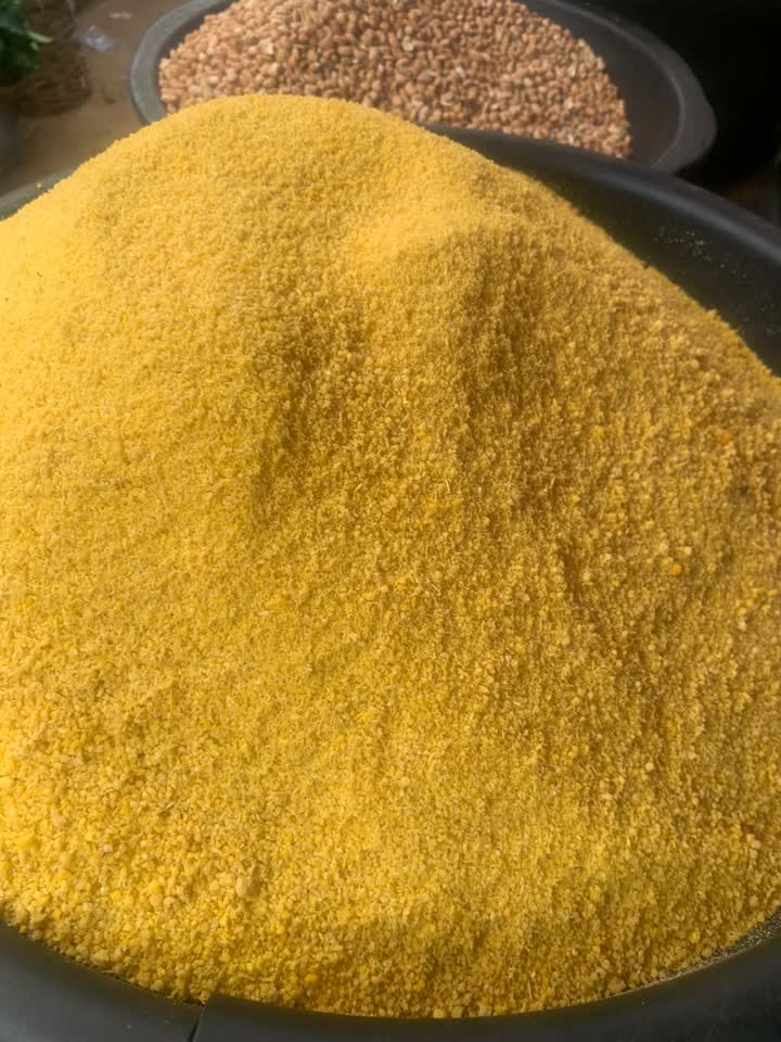 A golden mound of freshly milled yellow garri in a wide bowl